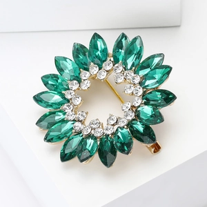 Gros plan d'une broche ronde florale avec strass émeraude et placage en alliage doré