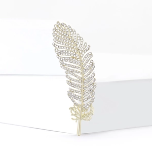 Macro shot of elegant gold feather brooch with shimmering crystal rhinestone inlay