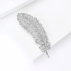 Macro shot of a silver leaf brooch with sparkling crystals on a white geometric background