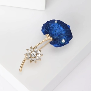 Détail d'une broche lotus avec feuille bleue texturée, perles naturelles et fleurs en strass