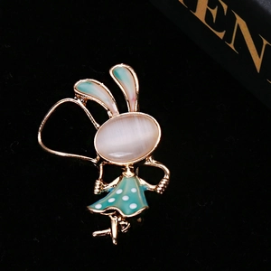 Gros plan d'une broche lapin en or avec œil de chat et émail sarcelle sur velours noir