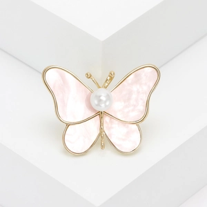 Macro detail of butterfly brooch with pink marble wings and white pearl center on gold frame
