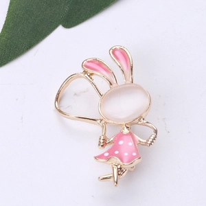 Détail d'une broche lapin dorée avec pierre opale et jupe rose à pois blancs