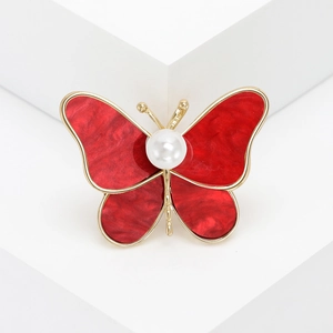 Elegant gold butterfly brooch with deep red wings and a large white center pearl