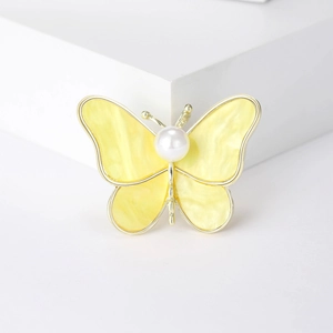 Detail of elegant gold butterfly brooch with shell texture and central pearl accent