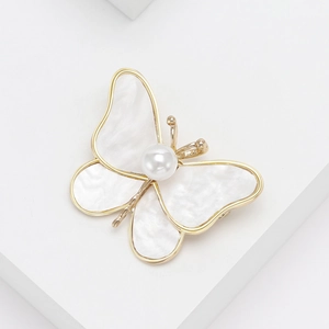 Elegant gold butterfly brooch with mother of pearl inlay and pearl on white steps