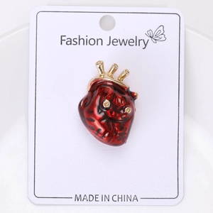 Vue détaillée d'une broche cœur anatomique en émail rouge et accents dorés sur carte de support