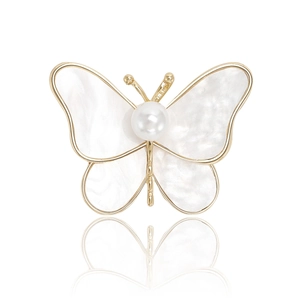 Elegant gold butterfly brooch with pearl and shell wings shown on a reflective surface
