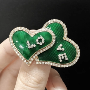 Detail of a double heart enamel brooch with sparkling rhinestones and LOVE lettering