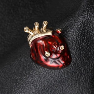 Détail macro de la broche cœur anatomique rouge avec couronne dorée et strass brillants