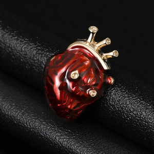 Détail macro d'une broche cœur anatomique en émail rouge avec serti couronne dorée