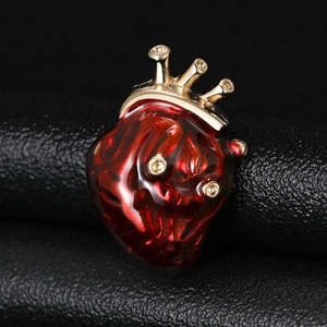 Macro de la broche cœur en émail rouge avec couronne dorée et détails en zircon