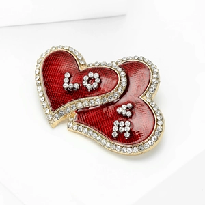 Detailed view of overlapping heart-shaped brooch with LOVE engraving and red enamel