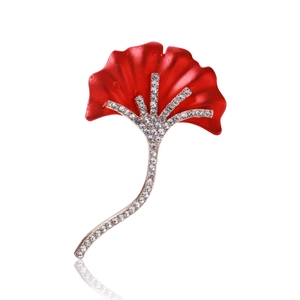 Détail d'une broche feuille de ginkgo rouge ornée de strass blancs sur métal doré