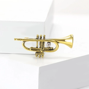 Vintage trumpet brooch pin in antique gold with a sparkling white cubic zirconia