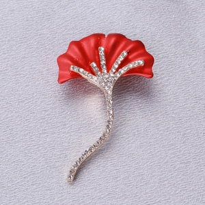 Détail macro d'une broche fleurie rouge avec strass scintillants sur tissu gris