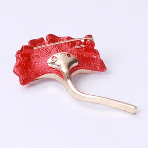 Détail de l'arrière d'une broche feuille rouge avec un fermoir doré de sécurité