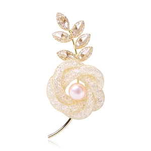 Vue détaillée d'une broche rose avec pétales en maille dorée et perle rose centrale