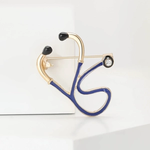 Macro detail of a golden stethoscope brooch with blue enamel inlay and sparkling rhinestone