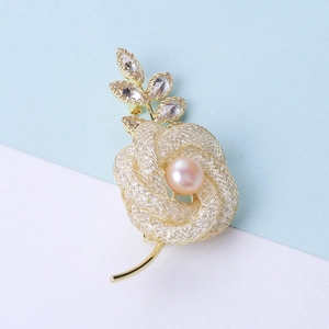 Détail de la broche rose dorée avec perle rose et accents de feuilles scintillantes