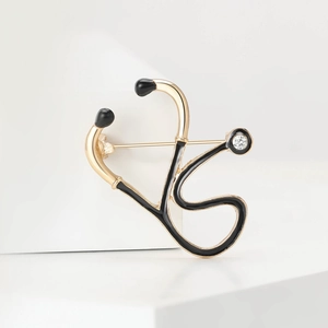 Detail of medical stethoscope brooch with black enamel, gold metal and crystal stone
