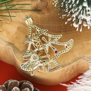 Golden Christmas tree brooch with red and green accents on a festive wooden background