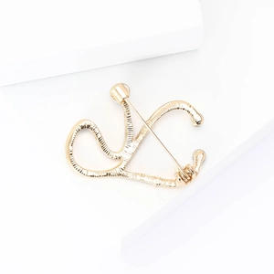 Macro shot of polished gold-tone metal V-shaped brooch on minimalist white geometric props