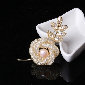Détail de la broche rose évidée avec pétales dorés tissés et perle rose centrale