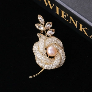 Détail d'une broche rose dorée avec perle rose et feuilles ornées de strass brillants