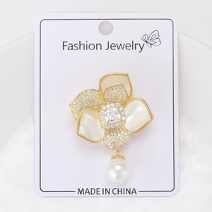 Broche camélia dorée avec pendentif perle et nacre détaillée sur carte à bijoux
