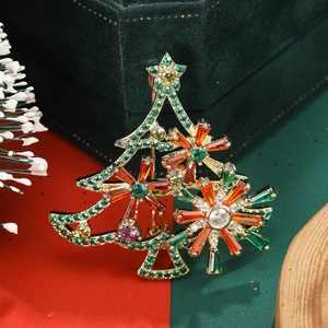 Close-up of golden Christmas tree brooch with colorful cubic zirconia on green velvet