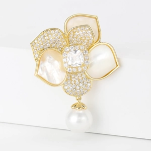 Détail de la broche camélia dorée avec perle pendante et pétales en nacre raffinés