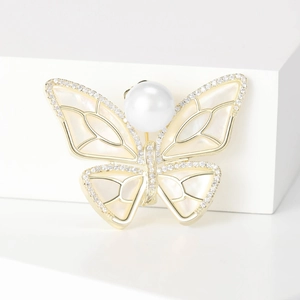 Detail view of gold butterfly brooch with mother of pearl wings and crystal accents