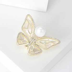 Macro shot of gold-plated butterfly brooch with shimmering shell inlay and white pearl