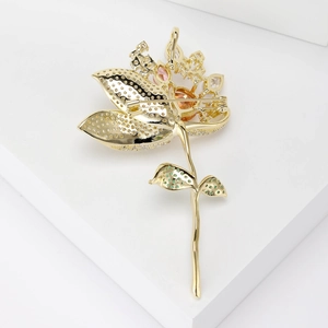 Broche lotus dorée élégante avec cristaux en dégradé et strass verts sur fond blanc
