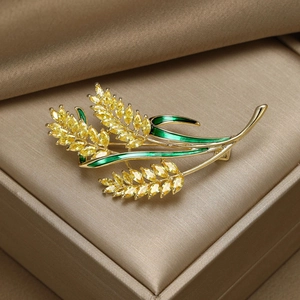 Close-up of golden wheat brooch with yellow stones and green enamel in a gift box