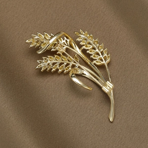 Elegant gold wheat sheaf brooch with enamel zircons on a brown satin background