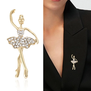 Élégante broche ballerine dorée avec cristaux blancs sur fond blanc et blazer noir