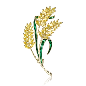 Elegant gold wheat brooch with yellow zircons and green enamel on a reflective surface