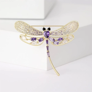 Close-up of golden dragonfly brooch with purple and clear zircon micro-pave setting