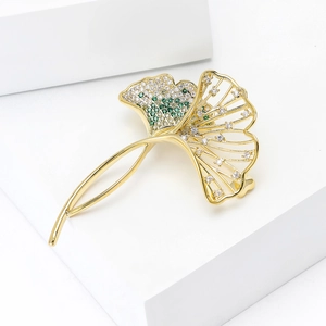 Detailed macro view of a gold ginkgo leaf brooch with intricate pavé cubic zirconia setting