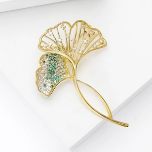 Macro detail of ginkgo leaf brooch featuring gold plating and green zircon inlay stones