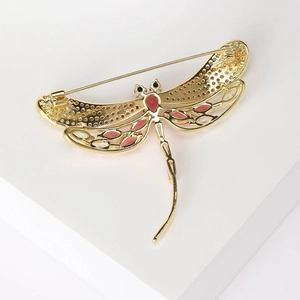 Detailed macro view of the golden dragonfly brooch featuring red drop-shaped crystals