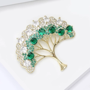 Vue macro d'une broche arbre de vie dorée avec des cristaux de zircon vert et blanc