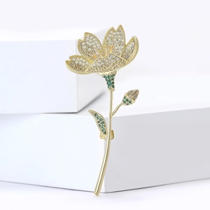 Eleganter Gold-Blumenanstecker mit Zirkonia-Steinen auf weißem geometrischem Podest