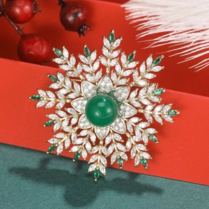 Detailed macro view of snowflake brooch with green emerald gems and festive gift box