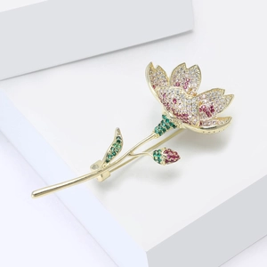 Makroaufnahme einer eleganten Blumenbrosche mit rosa Zirkonia und grünen Kristallblättern