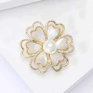 Élégante broche camélia avec pétales dorés, nacre et perle centrale sur fond blanc