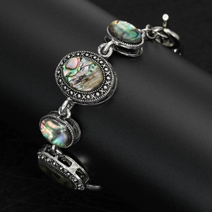 Vintage style silver metal bracelet with natural abalone shell inlays on black stand