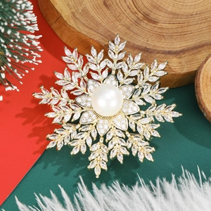 Detailed close-up of a golden snowflake brooch with a large central pearl and zircon